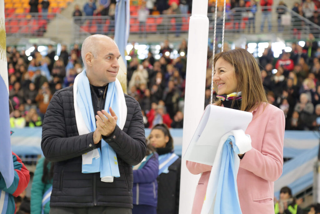 Junio 2019. Soledad Acuña y Horacio Rodríguez Larreta toman la promesa a la bandera a alumnos de 4.° grado en el Estadio Mary Terán de Weiss en el barrio de Lugano.
